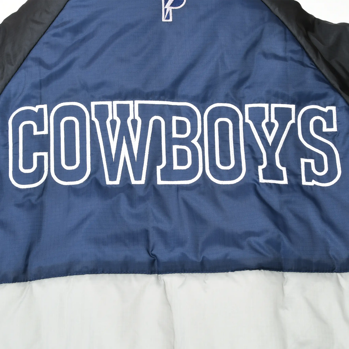 Close-up of large white-outlined COWBOYS lettering across navy jacket back