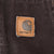 Close-up of square Carhartt logo patch stitched to brown jacket pocket