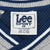 Close-up of Lee Sport neck label and navy, white, and gray striped V-neck collar