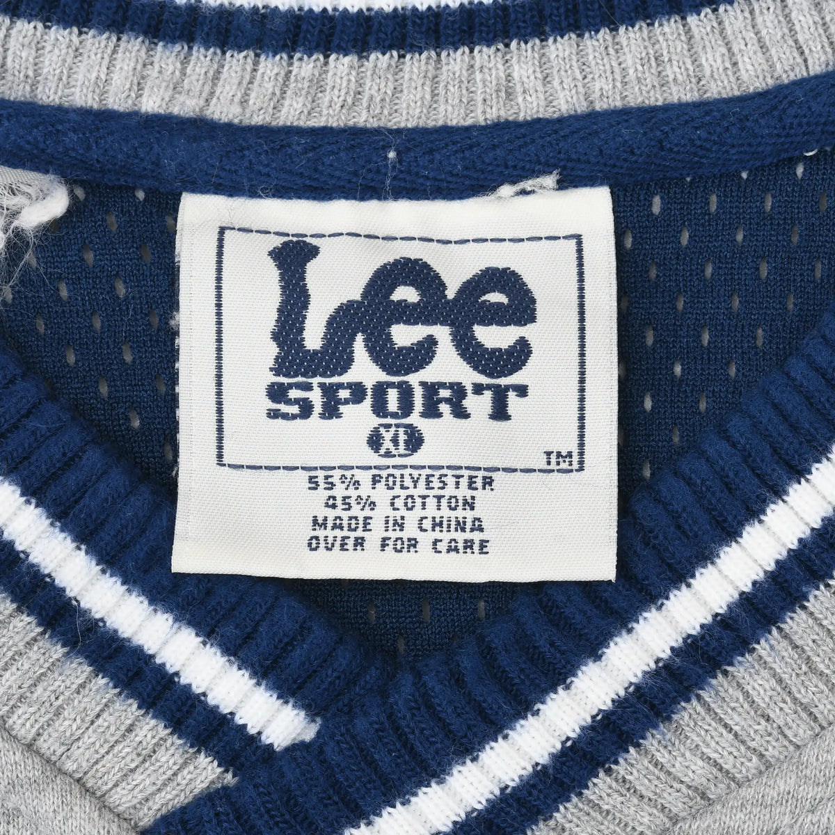 Close-up of Lee Sport neck label and navy, white, and gray striped V-neck collar