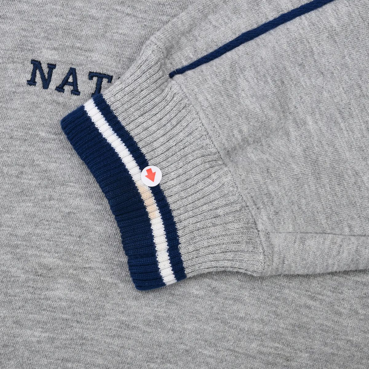 Close-up of gray sleeve and navy-and-white striped ribbed cuff with a small discolored area