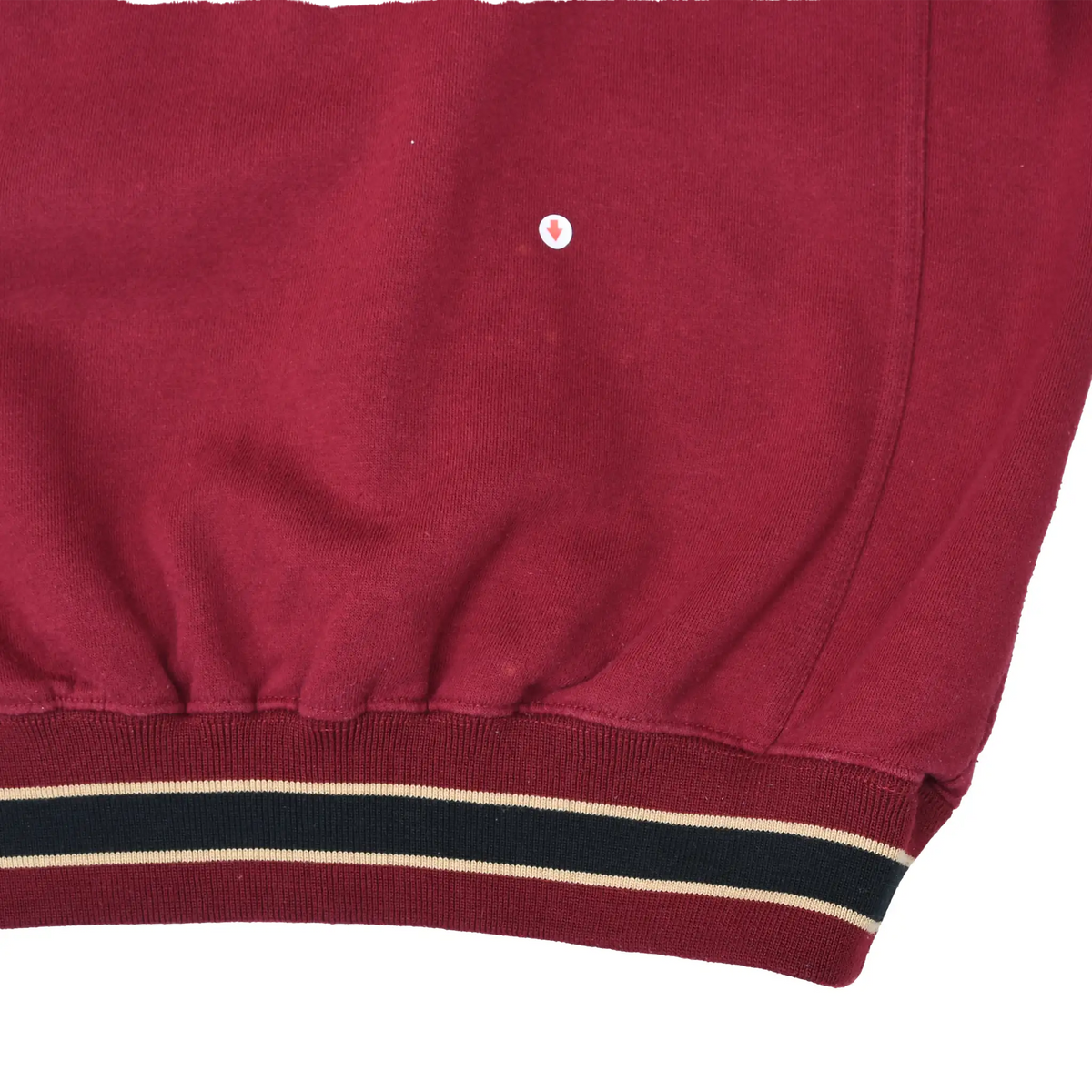 Close-up of lower front fabric with a small spot marked by an arrow and striped waistband
