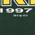 Close-up of white 1997 and TM copyright NFLP text printed on dark green sweatshirt fabric