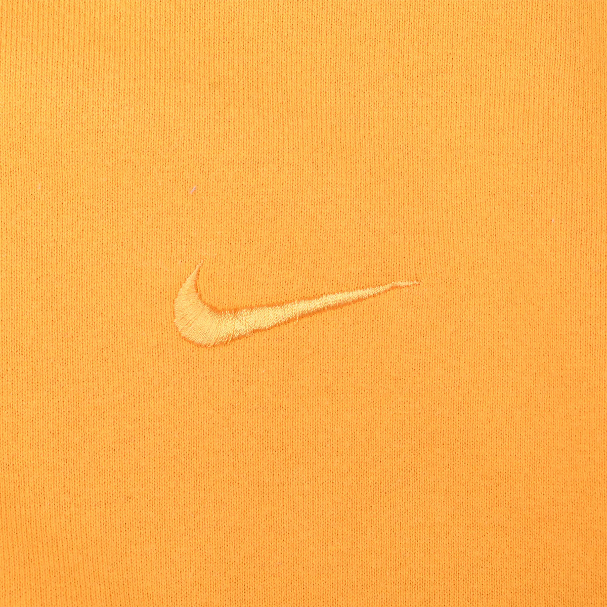 Close-up of tonal Nike Swoosh embroidery on yellow sweatshirt chest