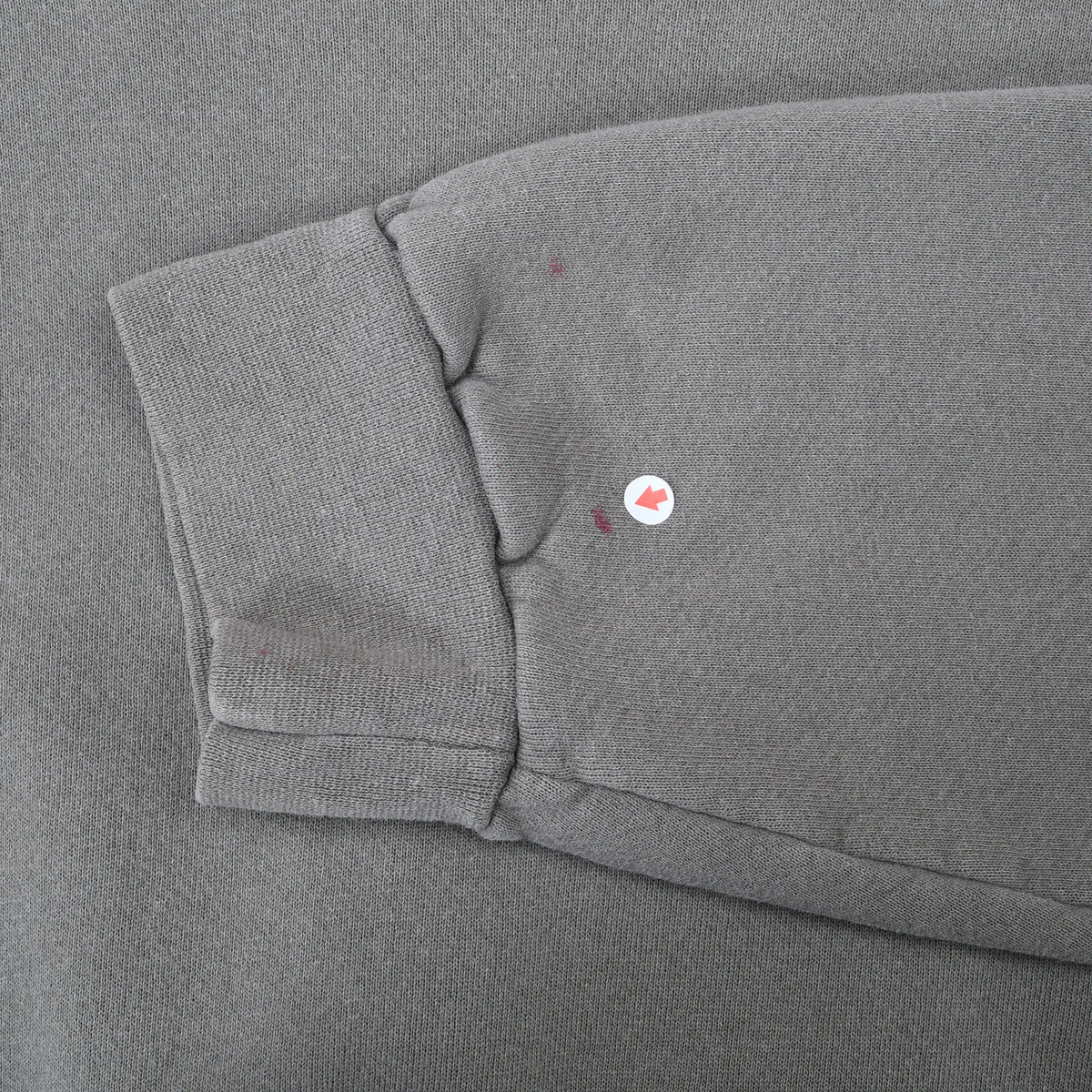 Close-up of sweatshirt sleeve cuff with small red marks near the seam