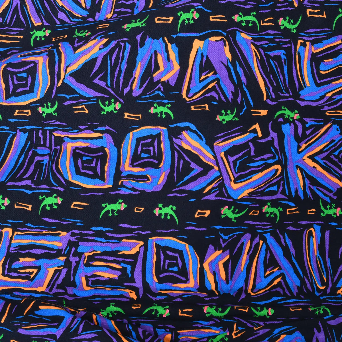 Close-up of black fabric with purple, blue and orange abstract shapes and small green geckos