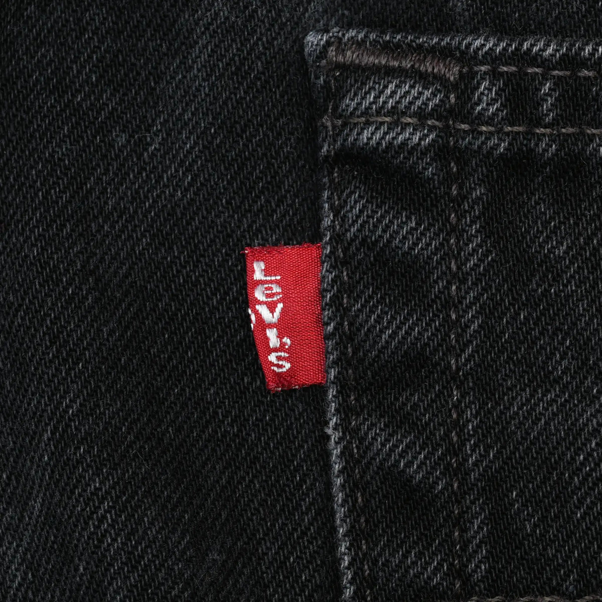 Close-up of red Levi's tab beside a back pocket on black denim
