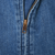 Close-up of brass-tone YKK front zipper on blue denim jacket