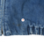 Close-up of small discolored spot near the elasticated hem of blue denim jacket
