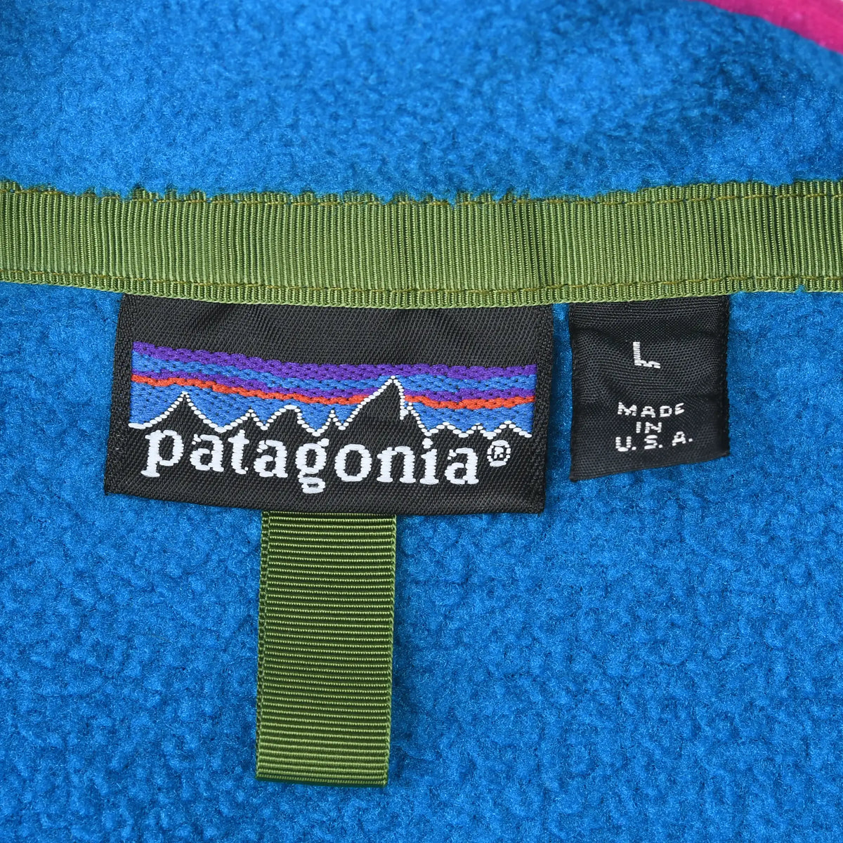 Close-up of Patagonia neck label, large size tag, and Made in USA tag on blue fleece