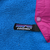 Close-up of Patagonia logo tab beside magenta snap chest pocket