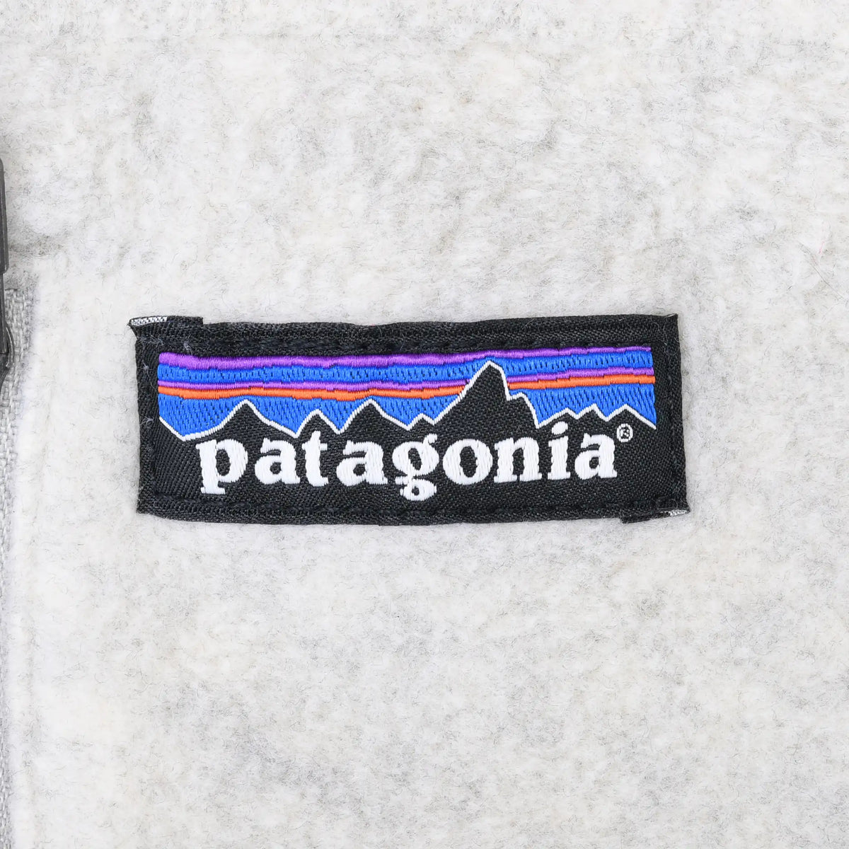 Close-up of Patagonia mountain logo patch on beige fleece
