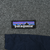 Close-up of Patagonia logo patch above the navy chest pocket flap on grey fleece