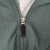 Close-up of green front zipper with black Nike Swoosh pull tab