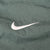Close-up of white Nike Swoosh embroidery on green jacket fabric