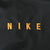 Close-up of orange NIKE embroidery on black jacket fabric