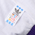Adidas Trefoil multilingual sizing tag against the windbreaker's white lining
