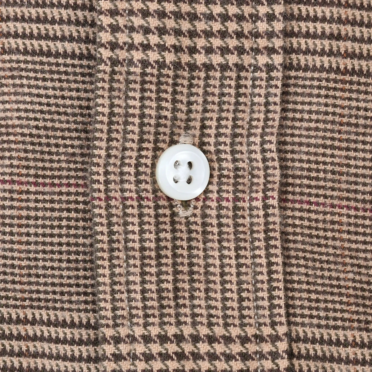 Close-up of white four-hole button and brown plaid pattern on Polo Ralph Lauren shirt