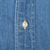 Close-up of white button, buttonhole, and stitching on blue denim shirt placket