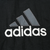 Close-up of large gray and white Adidas back logo embroidery on black fabric