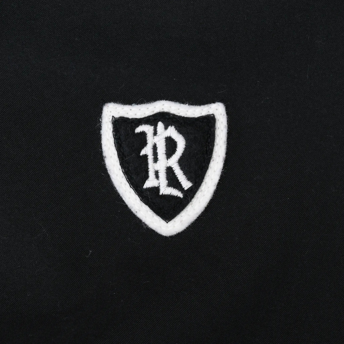 Close-up of white shield and PR monogram embroidery on black Polo Golf jacket