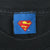 Blue neck tag with red and yellow Superman shield logo on black T-shirt