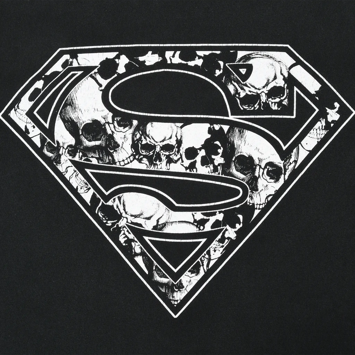 Close-up of white Superman shield graphic filled with skulls on black fabric
