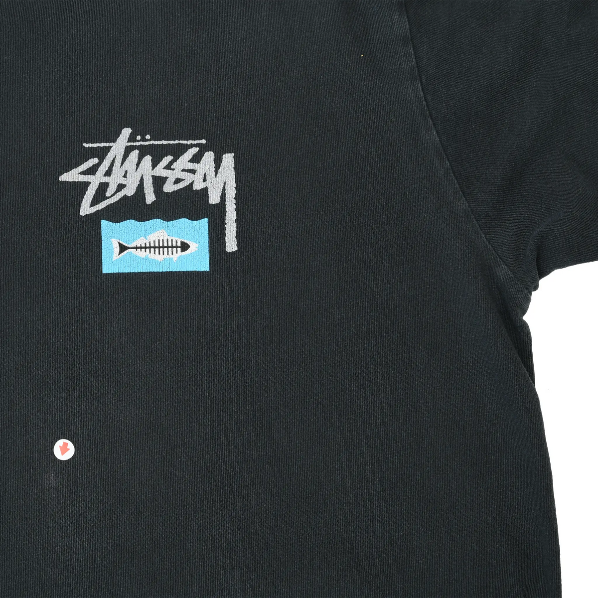 Close-up of left chest Stüssy logo and fish graphic on black T-shirt