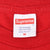 Supreme neck label on red T-shirt showing size M, 100% cotton, and made in USA
