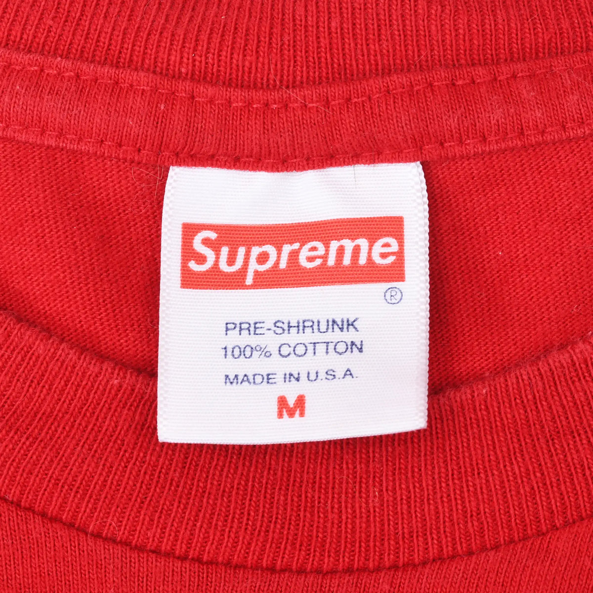 Supreme neck label on red T-shirt showing size M, 100% cotton, and made in USA