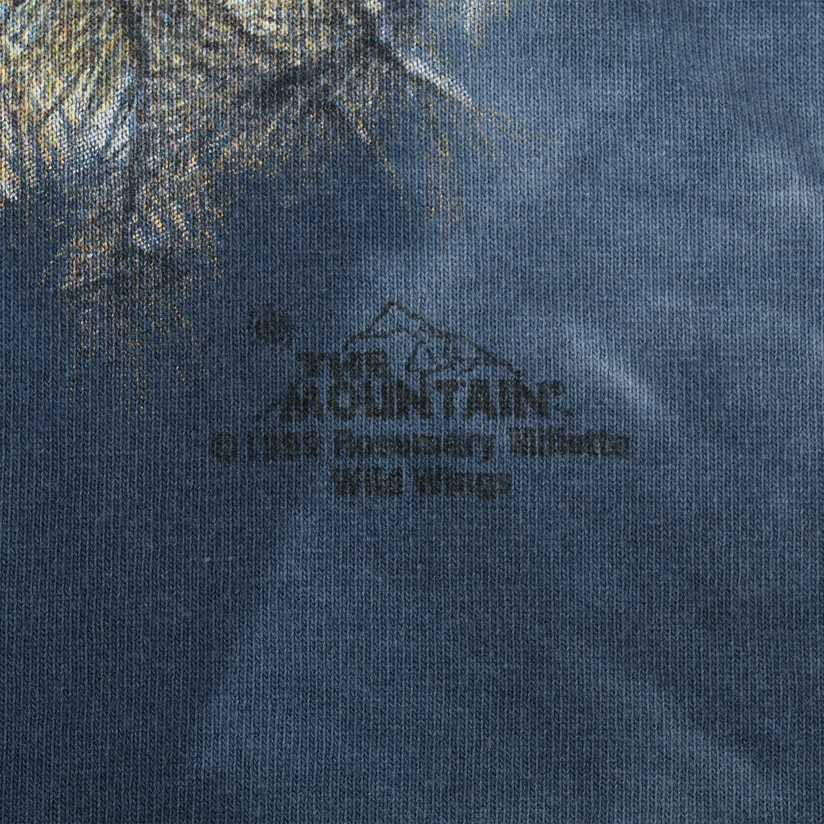 Close-up of The Mountain logo printed below the eagle graphic on blue fabric