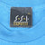 Close-up of black SSI Express XL neck label on blue T-shirt