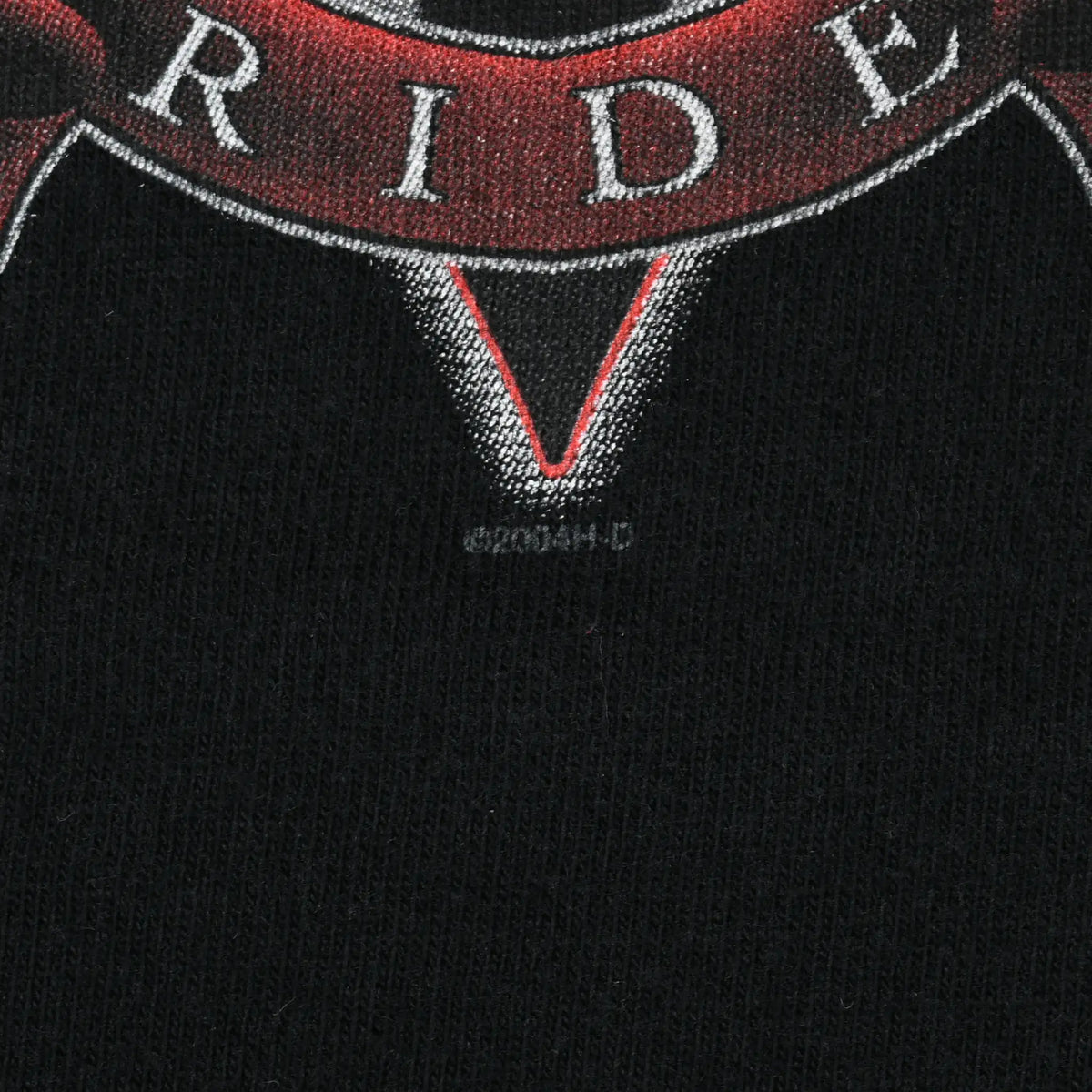 Close-up of black shirt fabric and lower edge of the embroidered-style Ride banner graphic