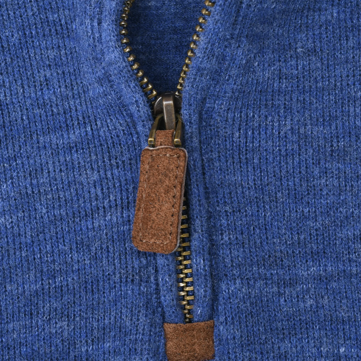 Close-up of quarter-zip closure with brown leather pull on blue sweater