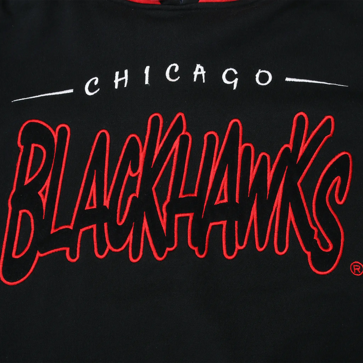 Close-up of red Chicago Blackhawks script embroidery on black sweatshirt fabric