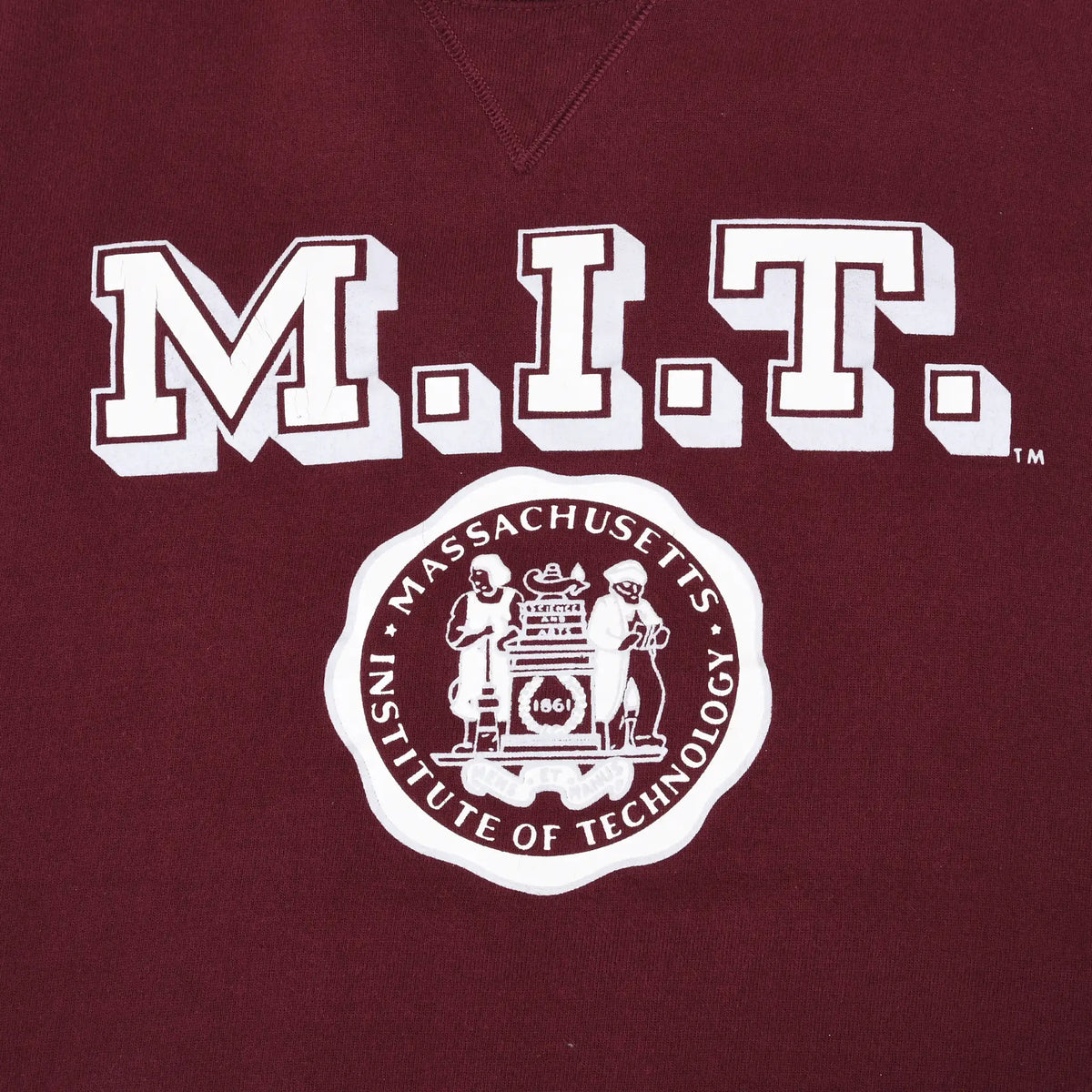Close-up of white M.I.T. lettering and Massachusetts Institute of Technology seal on burgundy fabric
