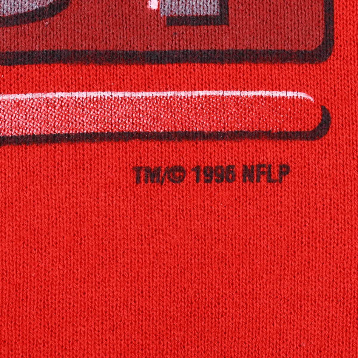 Close-up of 1996 NFLP copyright mark printed on red sweatshirt fabric
