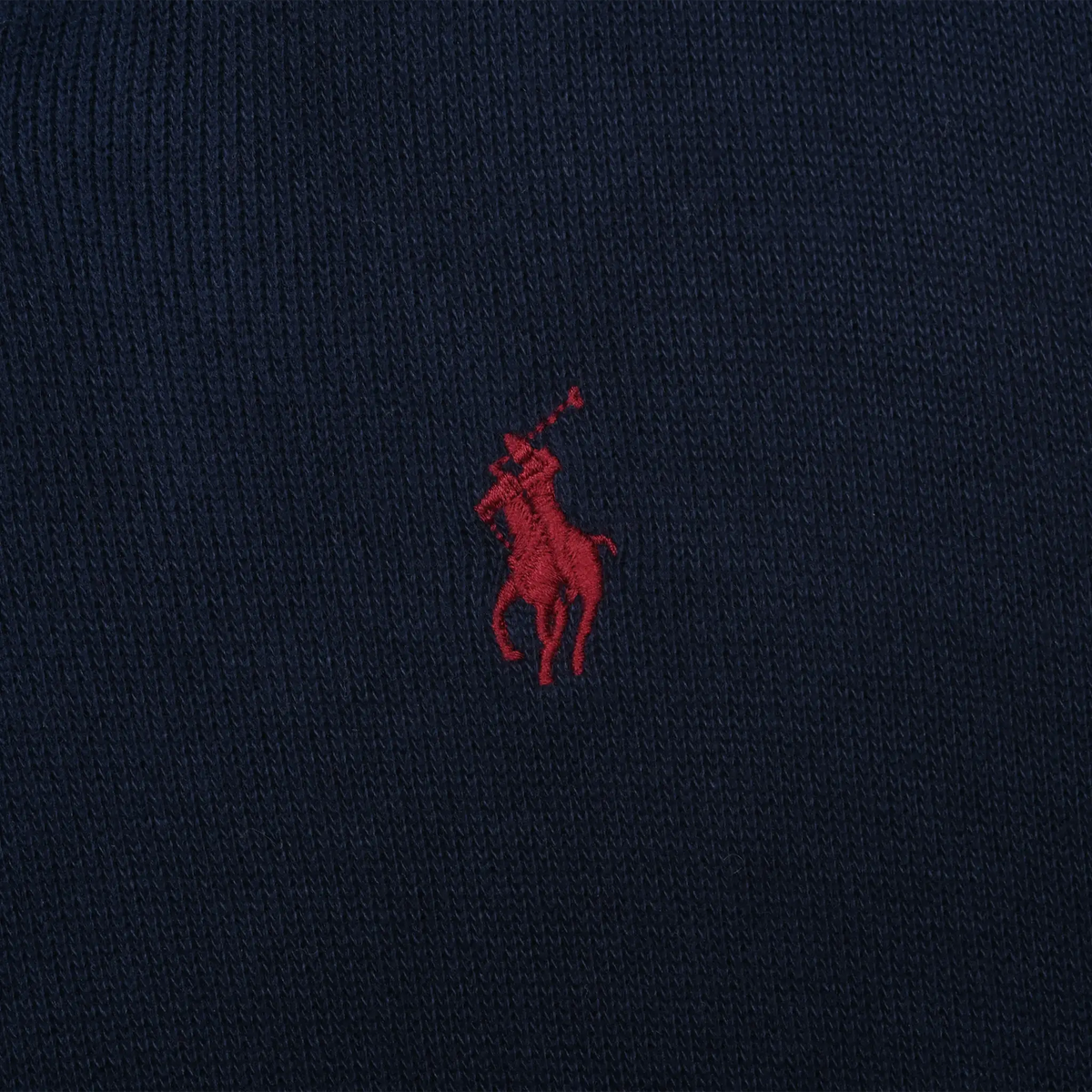 Close-up of red Polo pony embroidery on navy sweater fabric