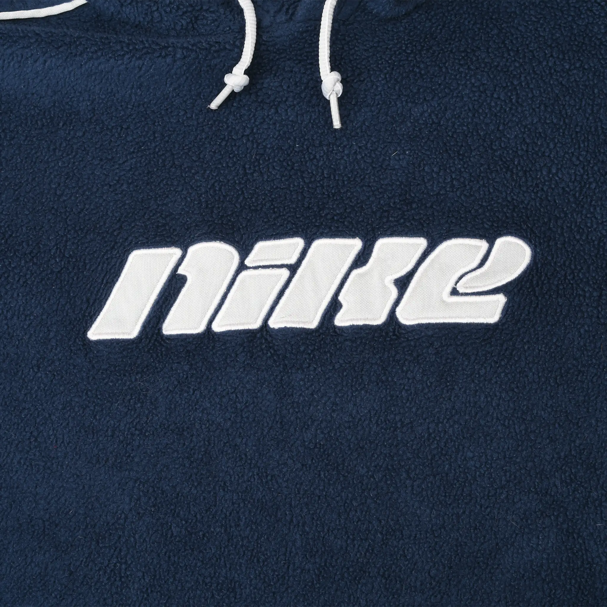 Close-up of white Nike spellout embroidery on navy fleece hoodie chest
