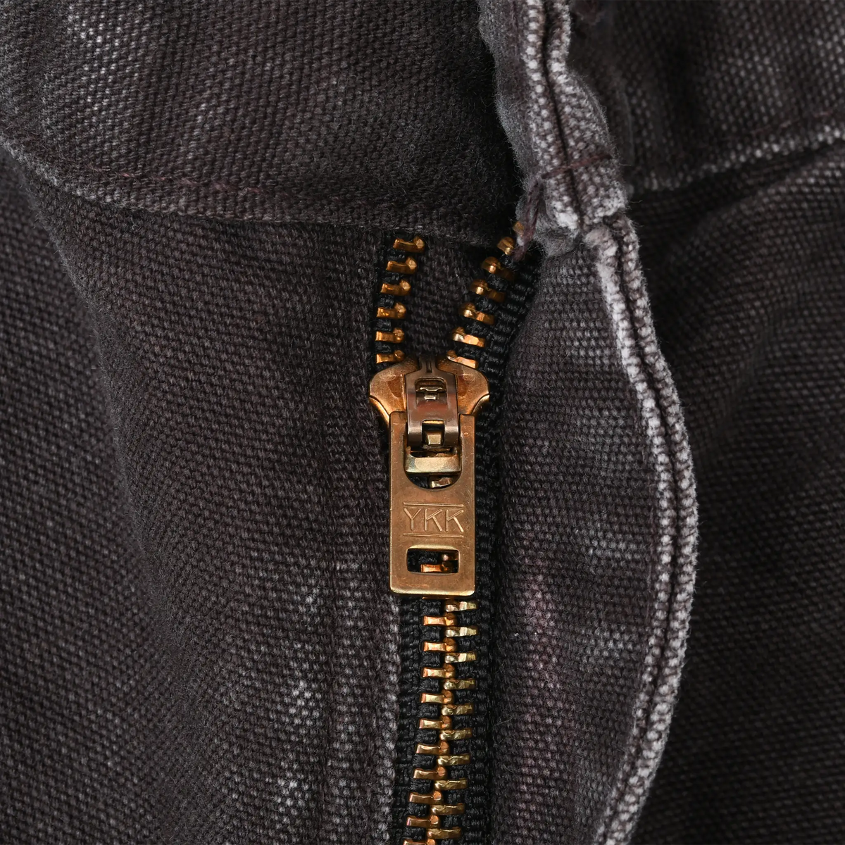 Close-up of brass-tone YKK zipper fly on dark brown Carhartt pants