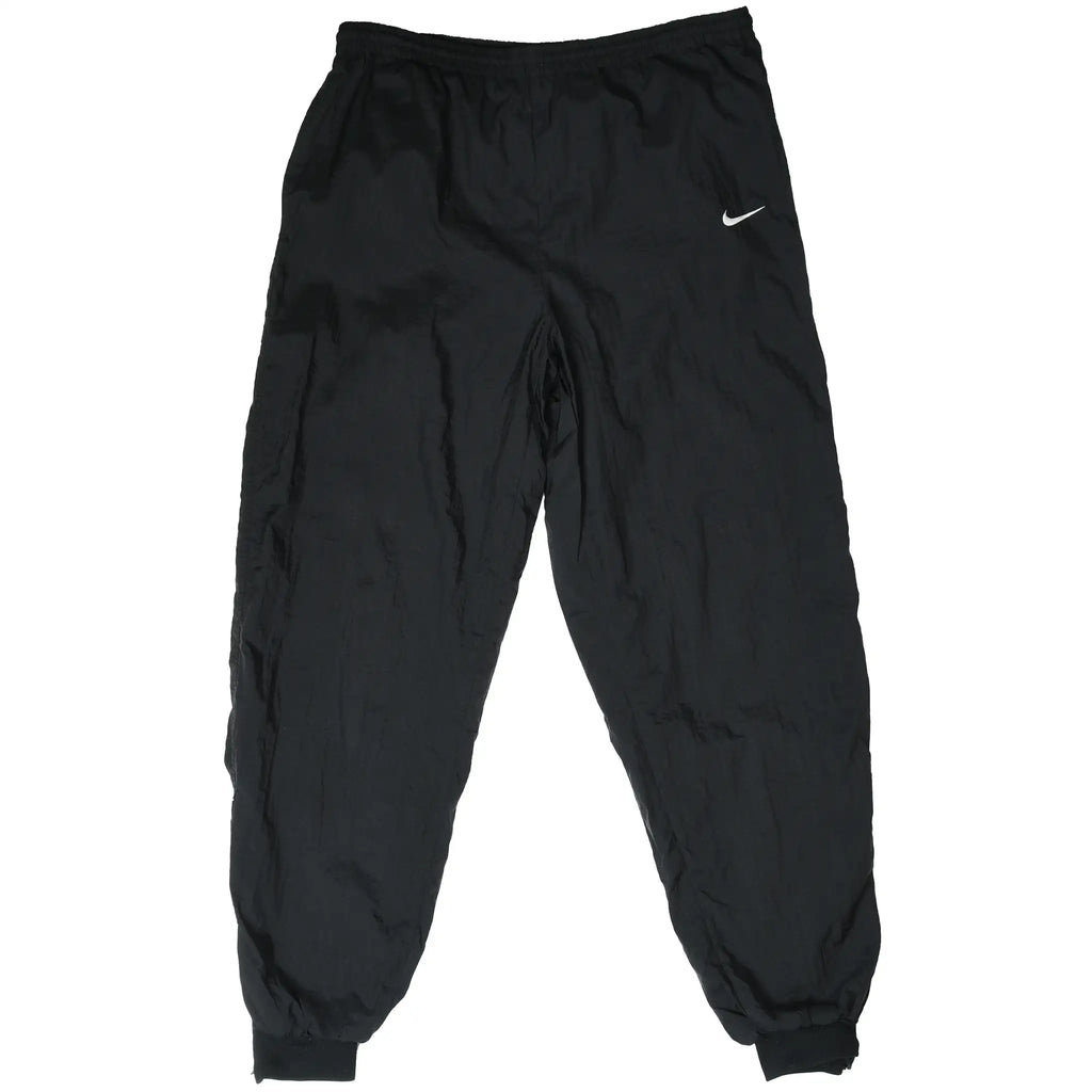 Front view of black Nike track pants with white Swoosh embroidery and elastic cuffs