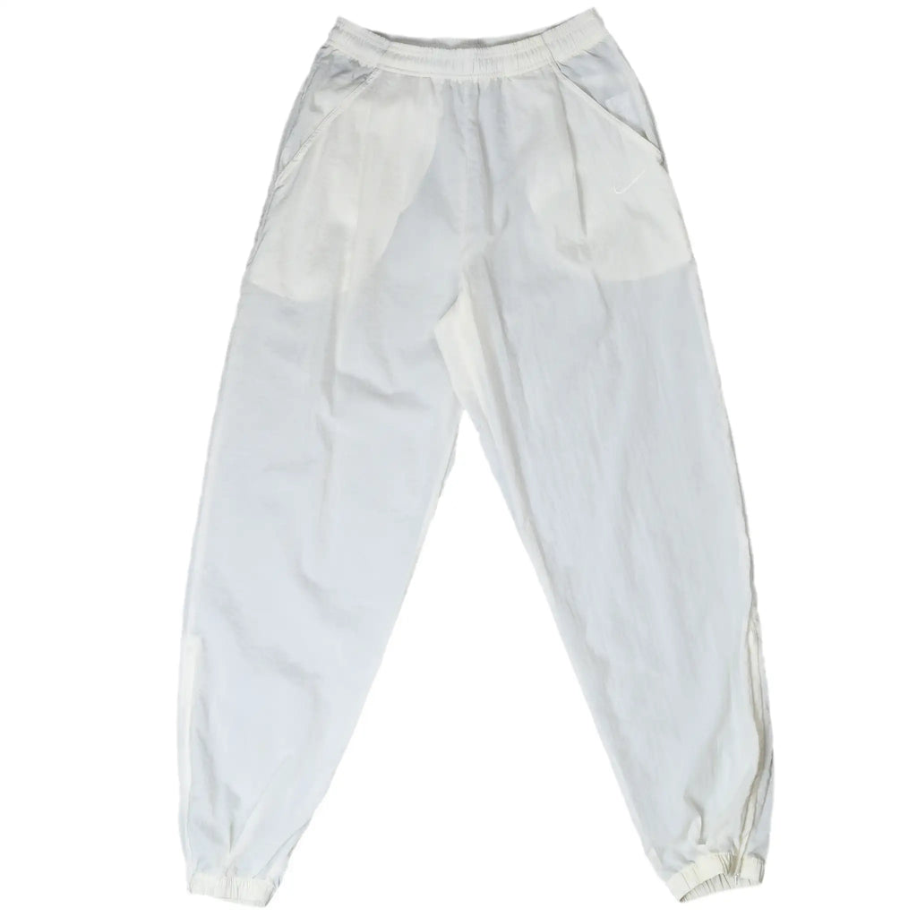 Front of white Nike track pants with side pockets, elastic cuffs, and tonal Swoosh embroidery