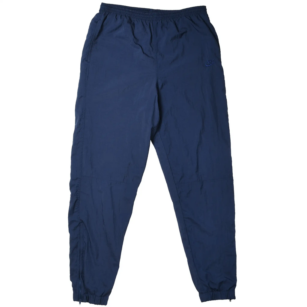 Front of navy blue Nike track pants with elastic waist, embroidered Swoosh, and zip cuffs