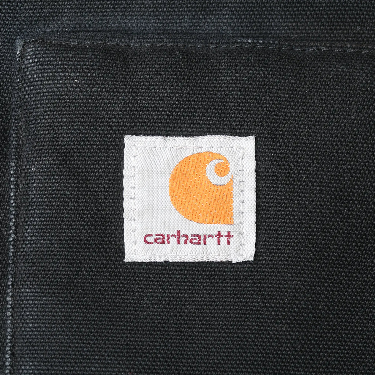Close-up of Carhartt logo patch stitched to the black front pocket