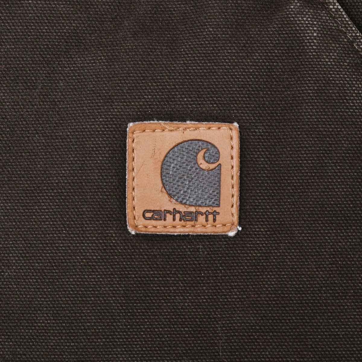 Close-up of square Carhartt logo patch on dark brown front pocket
