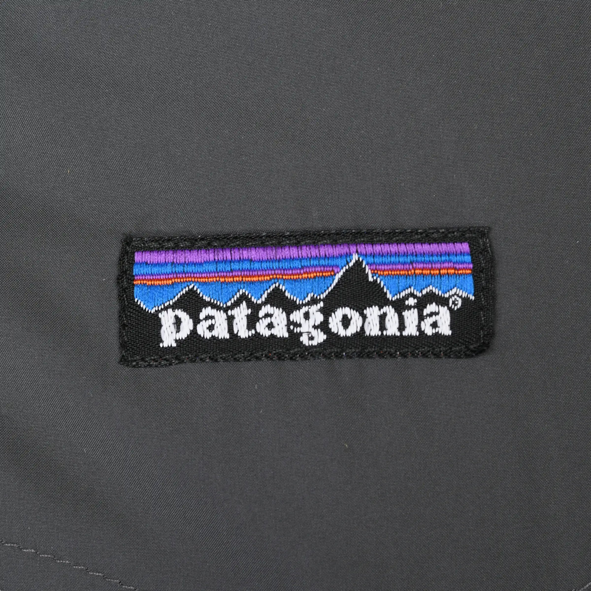 Close-up of embroidered Patagonia mountain logo patch on gray chest fabric