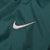 Close-up of white Nike Swoosh embroidery on dark green fabric