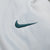 Close-up of small green Nike Swoosh embroidery on light grey fabric