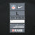 Close-up of Nike NFL On Field size L neck label on black jersey fabric