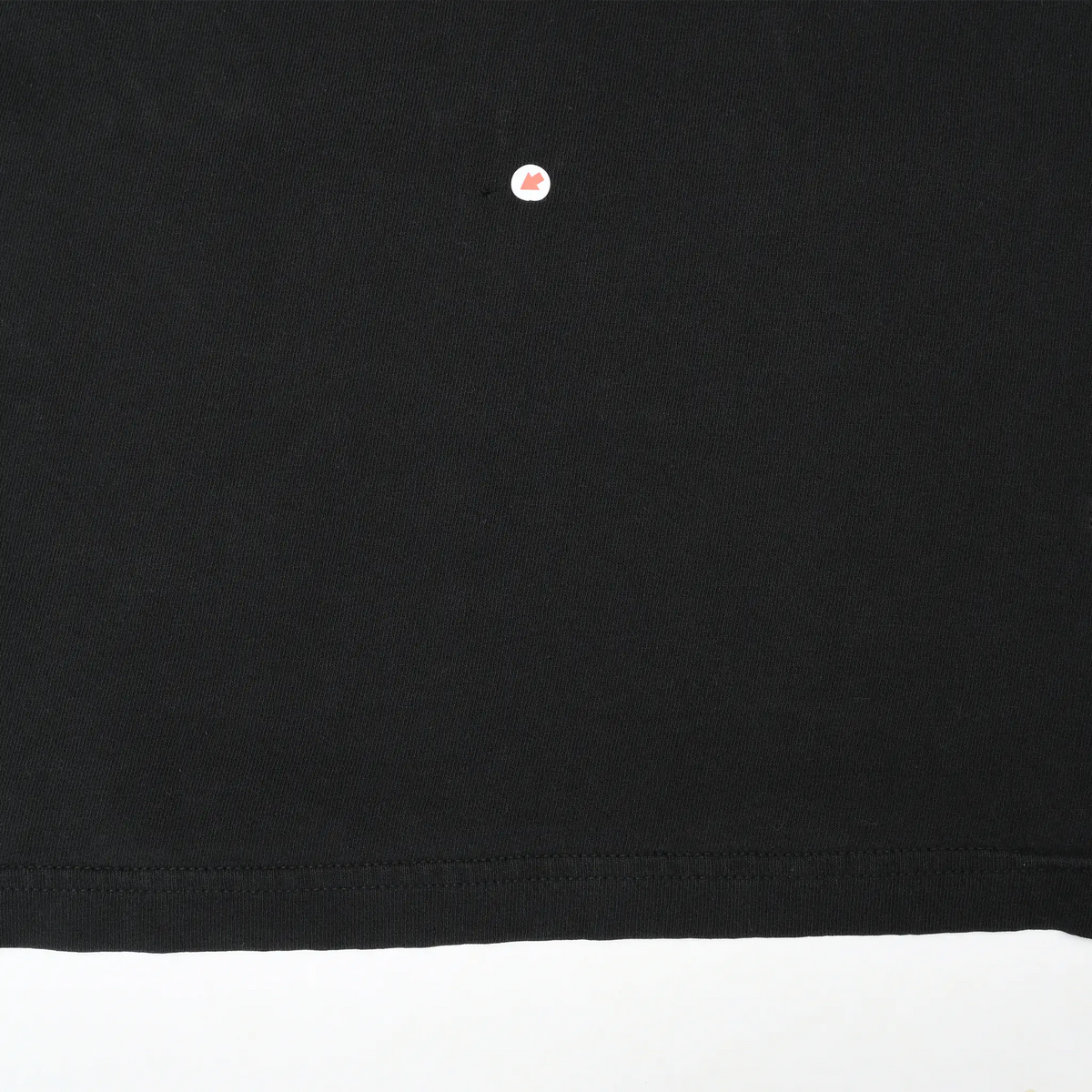 Close-up of black fabric near the bottom hem with a tiny marked spot